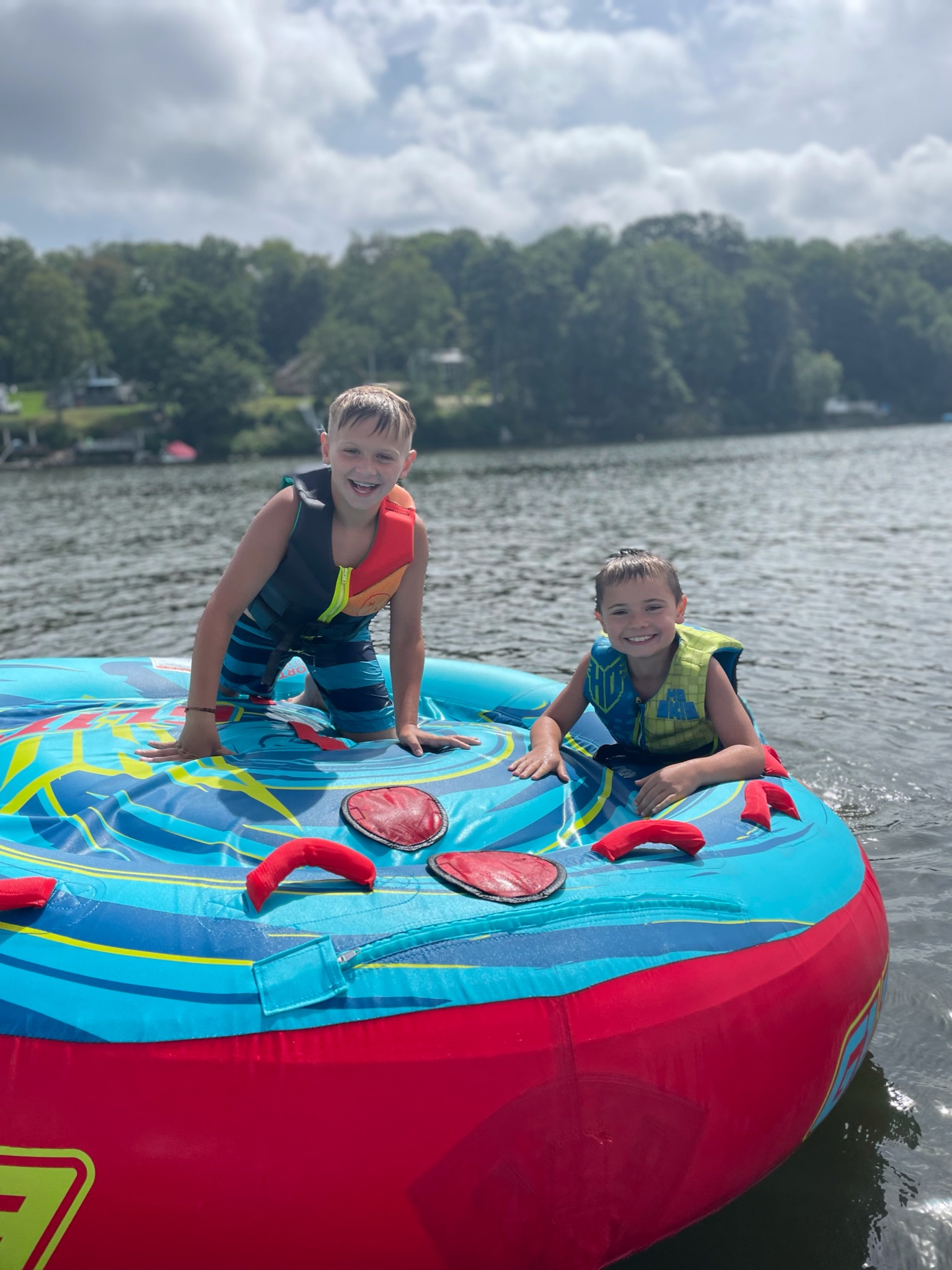 Kids laughing on a tube behind a boat on a Connecticut lake