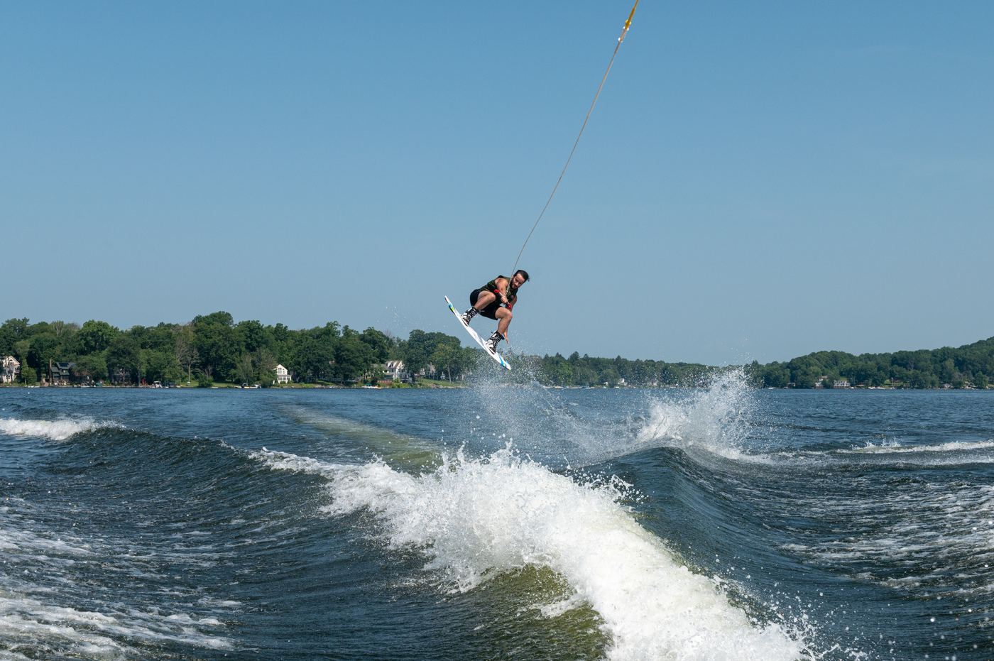 A guest mid-air on a wakeboard behind the boat